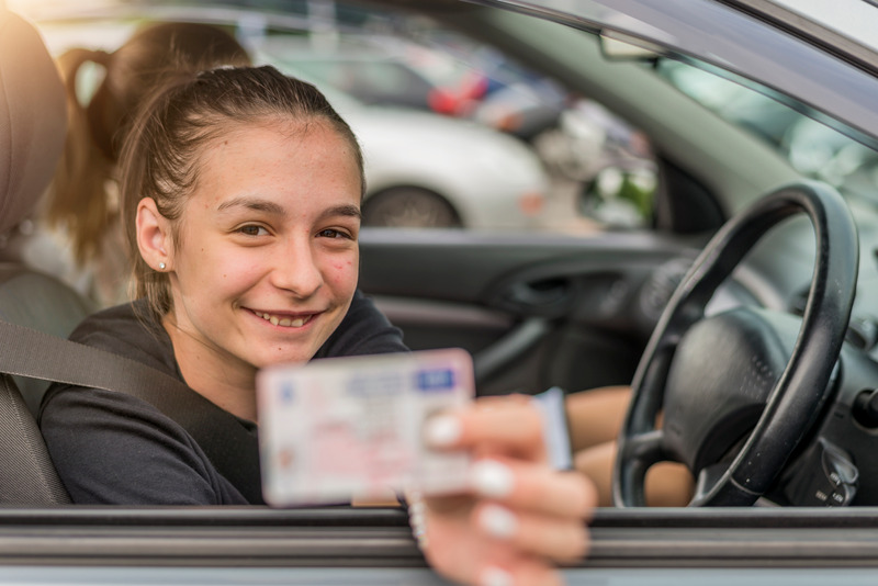 Teenager in car showing her drivers license
