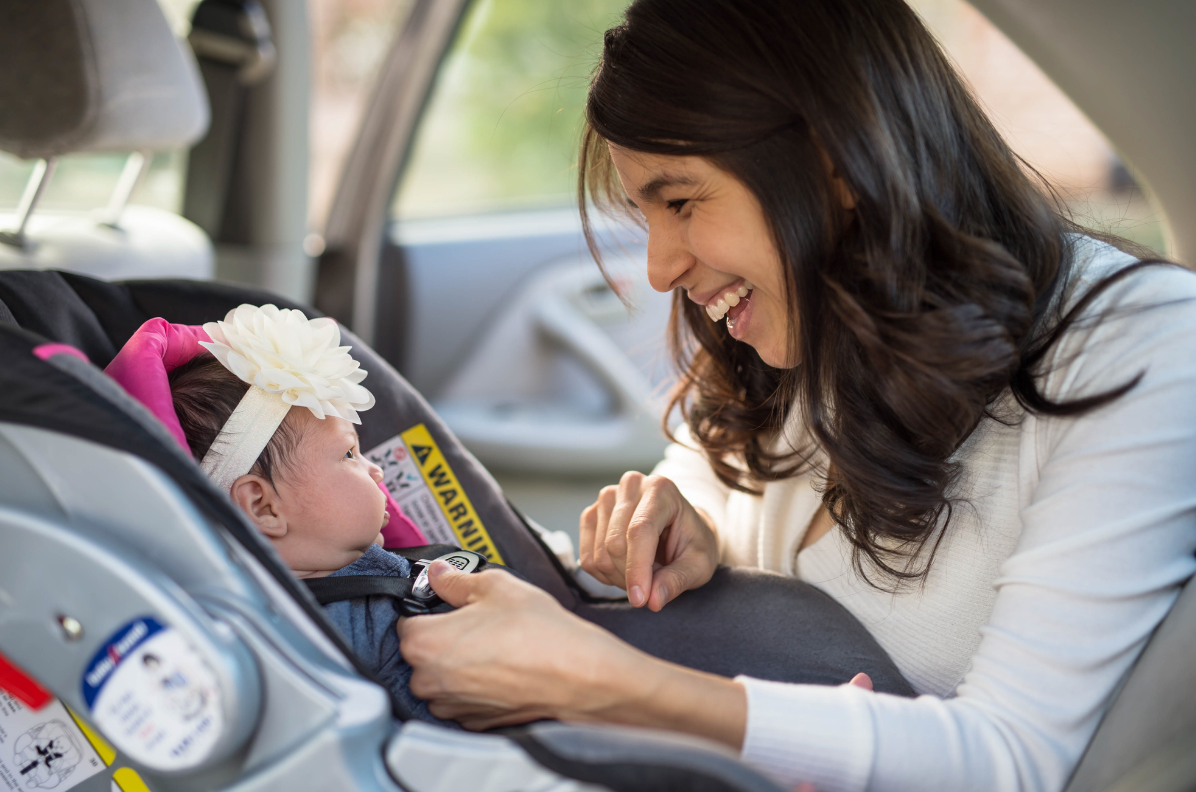 Mother buckling her child into a rear facing car seat 